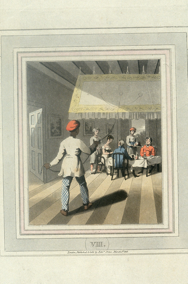 A young Indian servant pulls continuously on a cord attached to a large ceiling fan, in order to cool the room while his master eats dinner.”