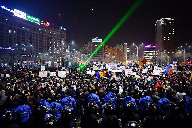 Romanian riot police stand guard as people demonstrate against controversial decrees to pardon corrupt politicians and decriminalize other offenses in front of the government headquarters in Bucharest, on February 1, 2017. PHOTO: AFP