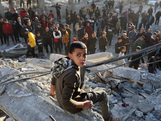 A Palestinian child on the rubble left by an Israeli strike on Nuseirat refugee camp, on December 13, 2024. Reuters