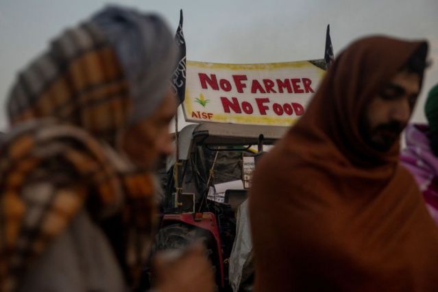 farmers stand next to a fire as they warm themselves on a cold winter morning at the site of a protest against new farm laws at singhu border near new delhi india december 21 2020 reuters