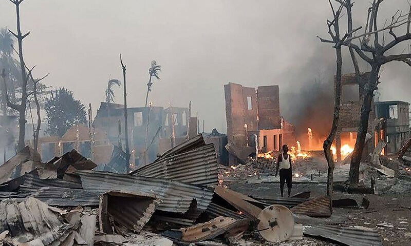 a man stands near a burning house at the site of a suspected air strike carried out by myanmar s military at kyauk ni maw village in western rakhine state photo afp