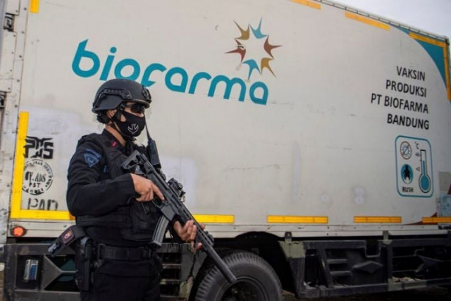 an armed police officer stands guard next to a truck containing sinovac s vaccine for coronavirus disease covid 19 as it arrives at the cold room of indonesia s local health department in palembang afp