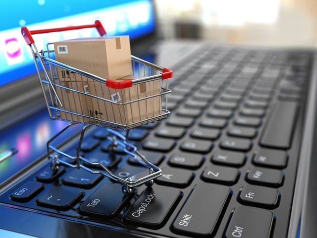 E-commerce. Shopping cart with cardboard boxes on laptop. 3d