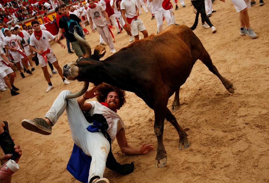 A bull hits a reveller as he falls down in the bull ring after the running of the bulls at the San Fermin festival. PHOTO: Reuters