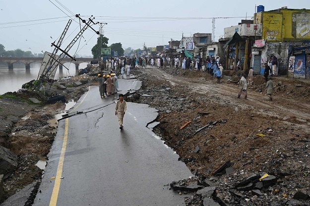 People stand on a damaged road in an earthquake-hit area on the outskirts of Mirpur. PHOTO: AFP