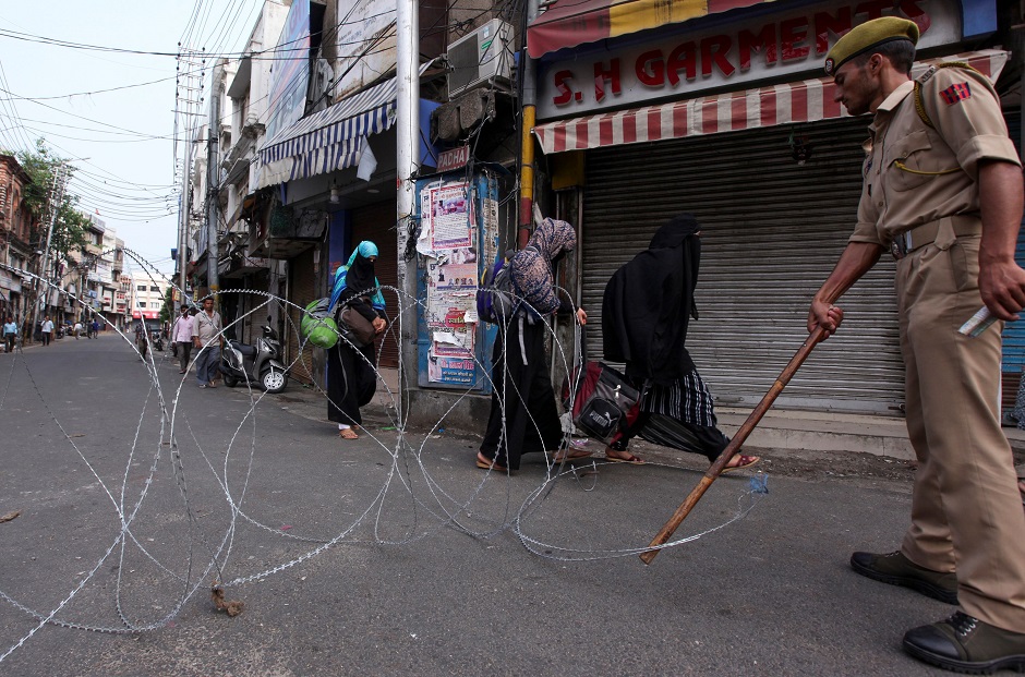 A policeman stands guard on a street as people walk paste in Jammu on August 6, 2019. (Photo: Rakesh BAKSHI / AFP)