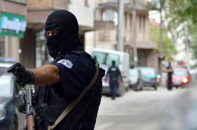 a masked police officer gestures as he stands guard in front of a court in pristina september 17 2014 photo reuters