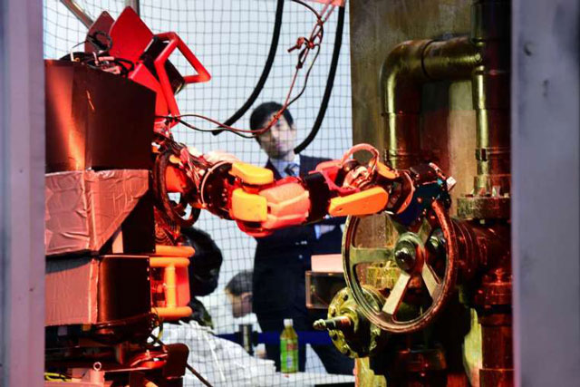 humanoid robot jaxon turns a handle of a valve during a demonstration of how the robot would work within a disaster area photo afp