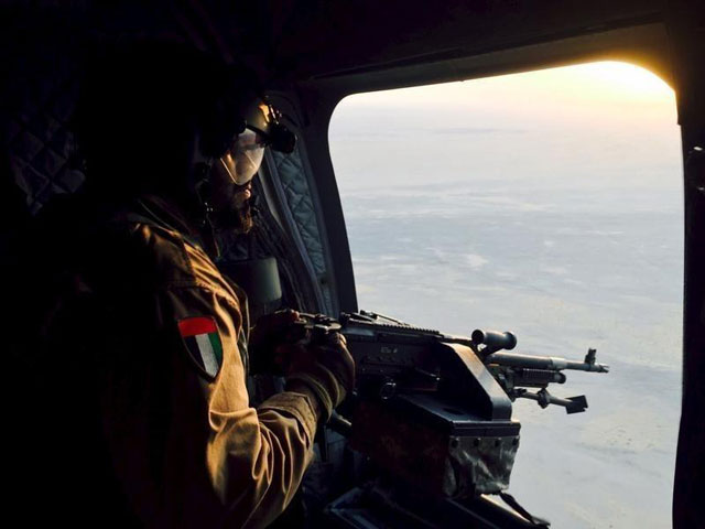 a soldier from the united arab emirates armed with a machine gun watches over yemeni territory while riding a chinook helicopter en route to a saudi led coalition air base in the kingdom september 17 2015 photo reuters