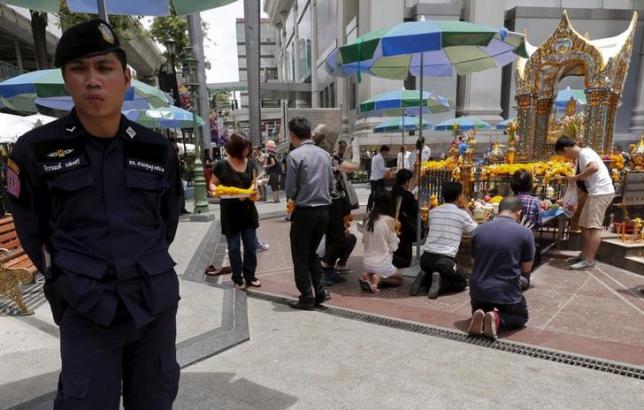 a thai police officer stands guard as people pray at the erawan shrine in central bangkok thailand photo reuters