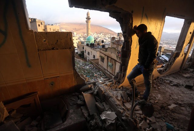 a palestinianm man looks at the rubble of the house of ragheb ahmad mohammad alawi a palestinian accused of masterminding the killing of a jewish israeli settler couple in the itmar settlement on october 1 after it was destroyed by israeli authorities in the west bank city of nablus early in the morning of december 3 2015 photo afp