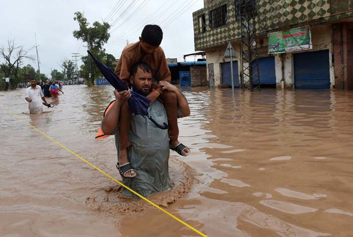 people walk through a flooded area of peshawar on july 26 2015 photo afp