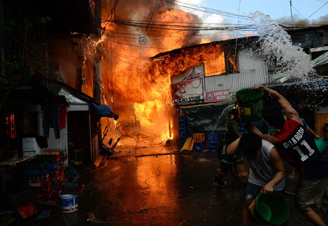 residents trying to put out a fire react as a cooking gas tank exploded from a burning house after a fire hit a shanty town near a jail building in manila on december 4 2015 photo afp