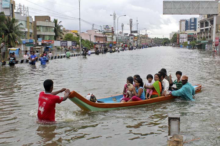 people travel on a boat as they move to safer places through a flooded road in chennai india december 2 2015 photo afp