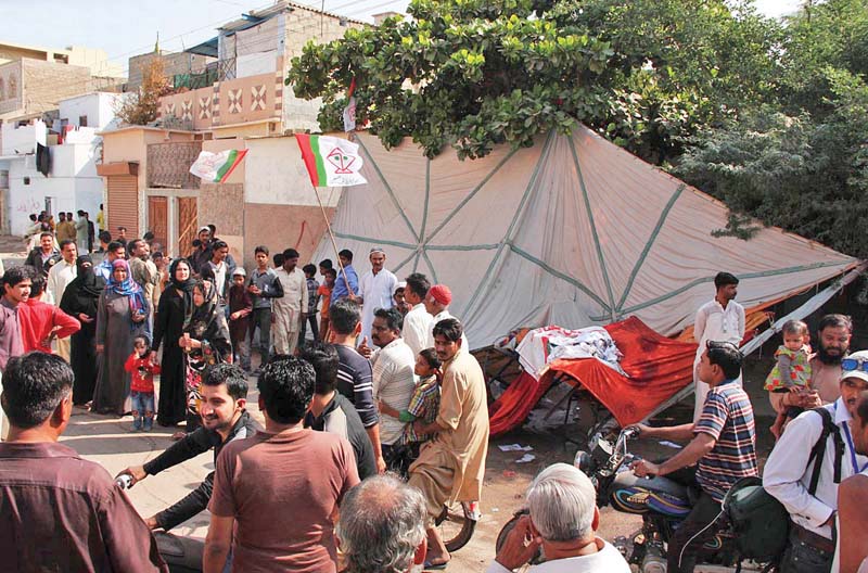 people gather at a fallen election camp in landhi the area witnessed clashes between supporters of arch rivals muttahida qaumi movement and muhajir qaumi movement haqiqi on the election day photo file