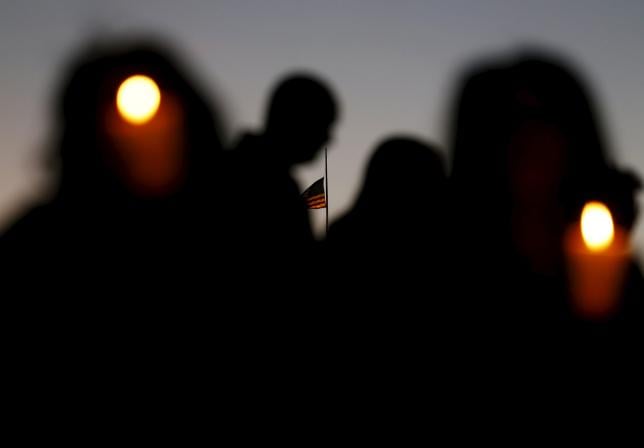 a u s flag flies at half mast at a downtown building as people hold candles at a vigil in san bernardino california december 7 2015 photo reuters