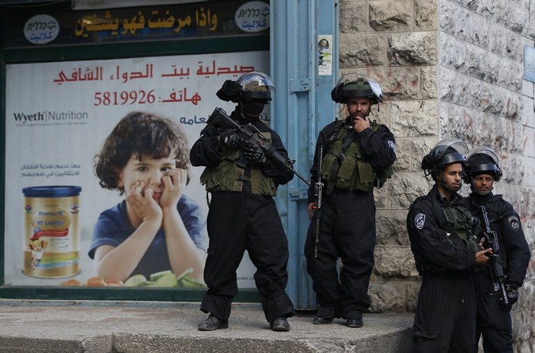 israeli security forces stand guard in the east jerusalem shuafat refugee camp ahead of a planned demolition of a home of a palestinian who carried out car ramming attack last year on december 2 2015 photo afp