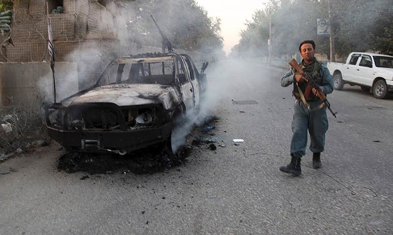 a file photo of an afghan policeman patrolling next to a burning vehicle in the city of kunduz afghanistan photo reuters