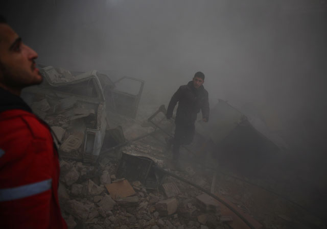 a member of the syrian arab crescent and a man look for survivors amid the rubble following air strikes in the rebel held town of douma on the eastern edges of the syrian capital damascus on december 13 2015 photo afp