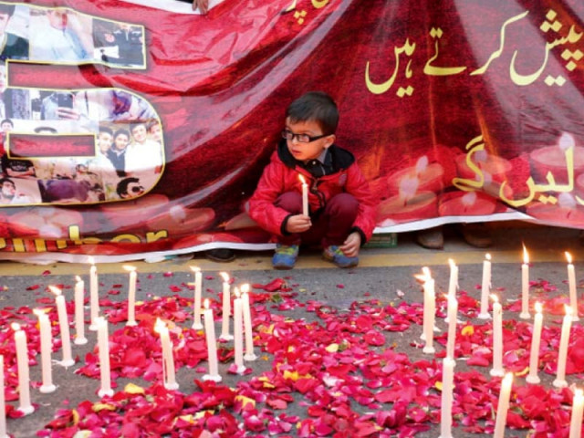 a boy sits under a banner at a vigil at liberty chowk photo shafiq malik express a boy sits under a banner at a vigil at liberty chowk photo shafiq malik express