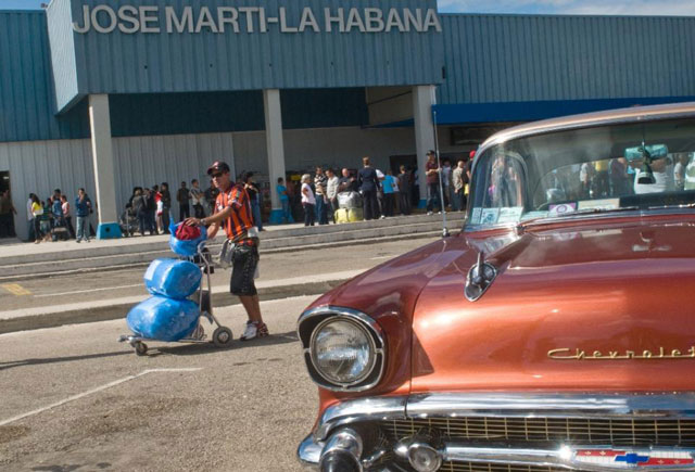 a cuban american pases by a vintage chevrolet as he arrives from miami at havana 039 s international airport december 24 2009 photo afp