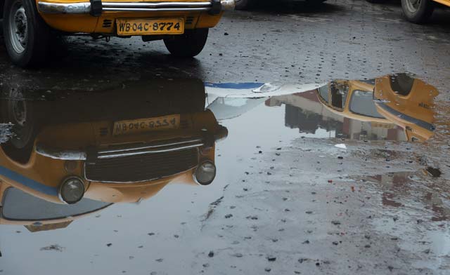 in this photograph taken on december 18 2015 indian taxis are reflected in a pool of water as their drivers wait for passengers in kolkata from london and paris to new delhi and sao paolo traditional taxi drivers united worldwide against uber in 2015 a year that saw riots legal battles and even a kidnapping in protest against the startup photo afp