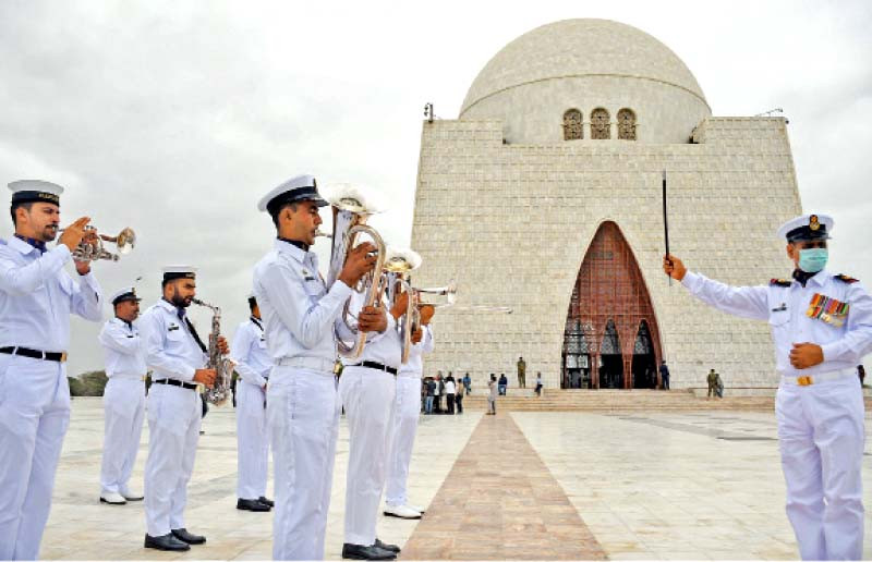 pakistan navy band plays at quaid s mazar frere hall illuminated in green lights while fishermen take out a boat rally and ssgc officials raise national flag on independence day photos express agencies