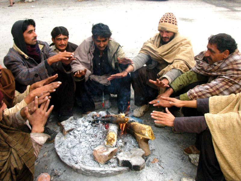 labourers burn firewood to keep themselves warm while fog hangs over the capital on saturday photos waseem nazir express