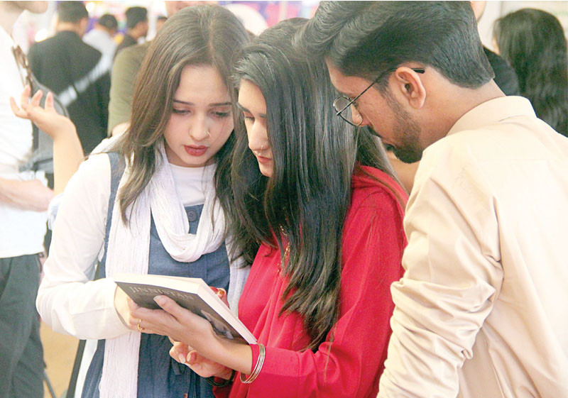 three students read the back cover of a book at a stall at the 15th klf on sunday photo online