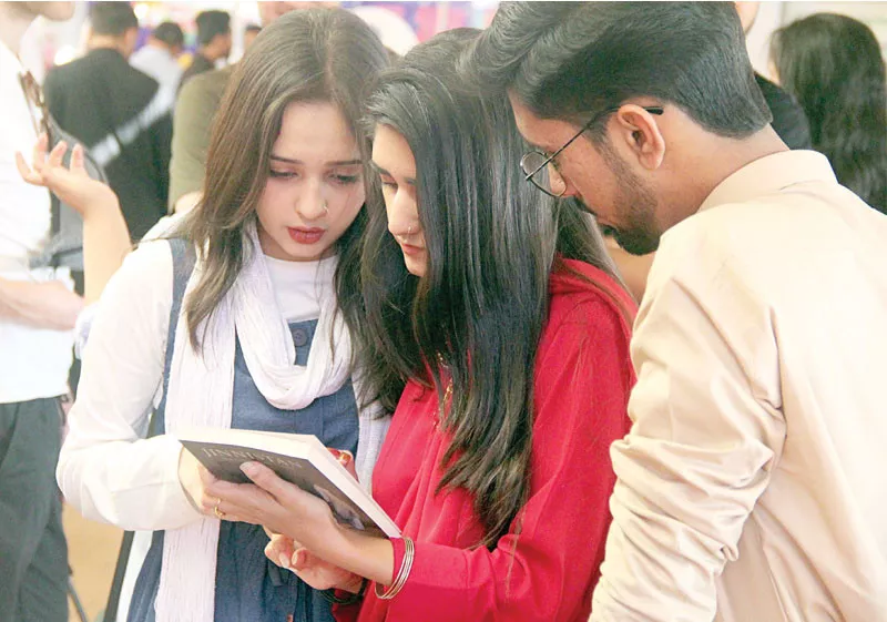 three students read the back cover of a book at a stall at the 15th klf on sunday photo online three students read the back cover of a book at a stall at the 15th klf on sunday photo online
