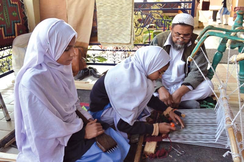 an artisan guides students how to weave at lok virsa photo express