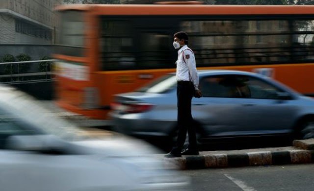 an indian traffic policeman with his face covered by a protective mask handles traffic at an intersection in new delhi on december 31 2015 as locals braced for a ban that will keep more than a million private cars from the roads photo afp