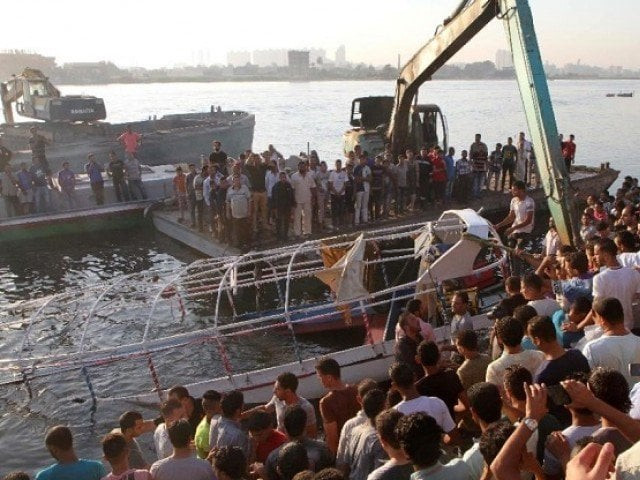 relatives and onlookers gather on the bank of the nile north of the egyptian capital cairo as the wreckage of a boat is pulled out of the water on july 23 2015 photo afp