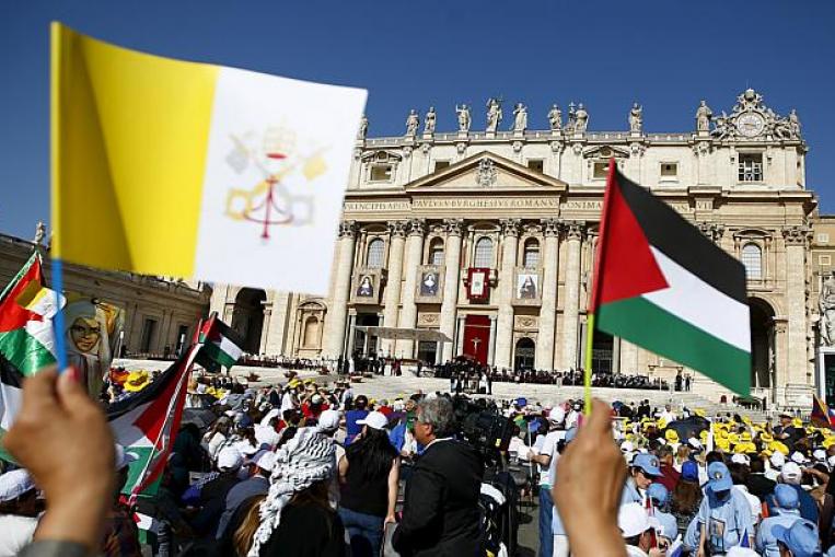 members of the faithful wave palestinian and vatican flags before pope francis leads a ceremony for the canonisation of four nuns at st peter 039 s square in the vatican city on may 17 2015 photo reuters