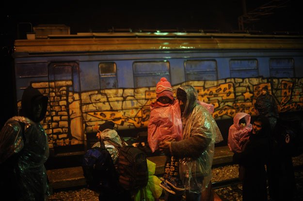 migrants and refugees wait to board a train under heavy rain at a train station in the southern serbian town of presevo on january 6 2016 photo afp