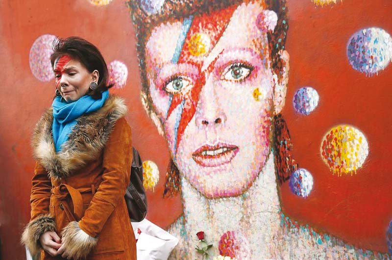 a fan wearing ziggy stardust style make up visits a mural of david bowie in brixton south london photo reuters