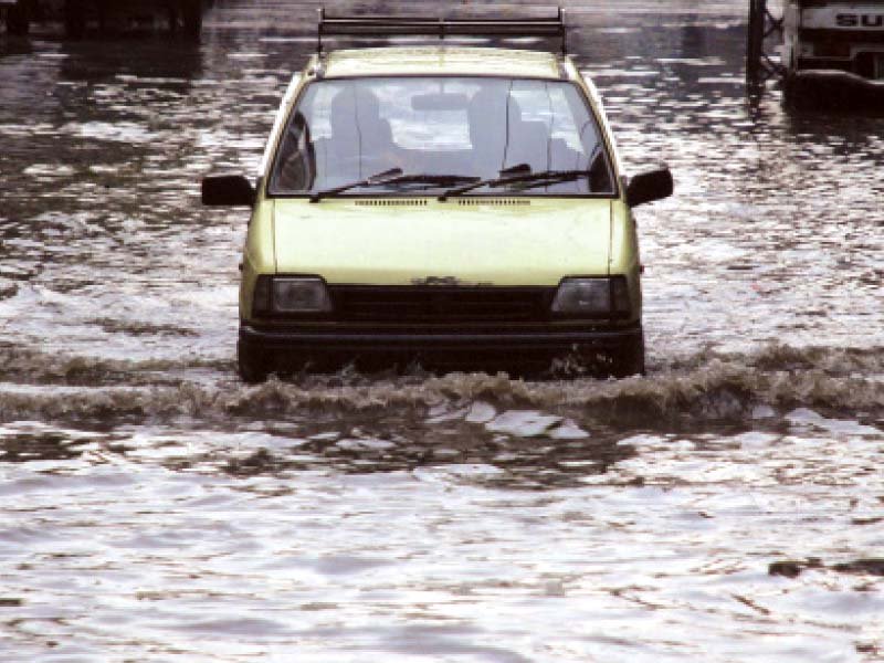 a taxi wades through rainwater accumulated on naz cinema road in rawalpindi while people purchase umbrellas from a vendor in islamabad s aabpara market photos zafar aslam mudassar raja