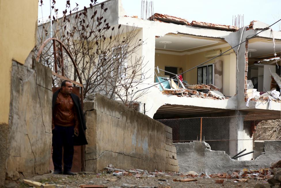 a man stands next to a building damaged after a truck bomb attack on a nearby police station in cinar in the southeastern city of diyarbakir turkey january 14 2016 photo reuters