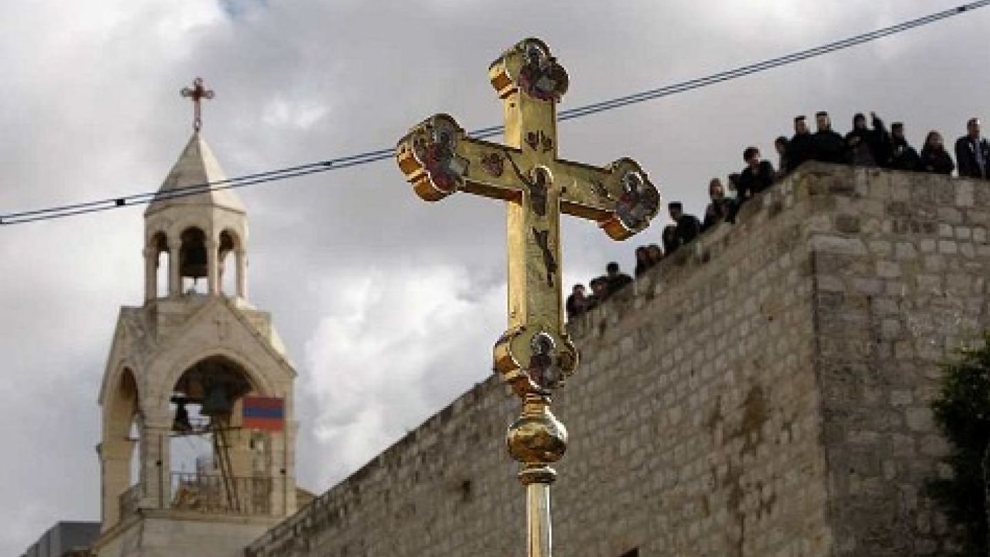 a crucifix is held up in front of the church of the nativity during the orthodox christmas procession in the west bank town of bethlehem january 6 2011 photo reuters