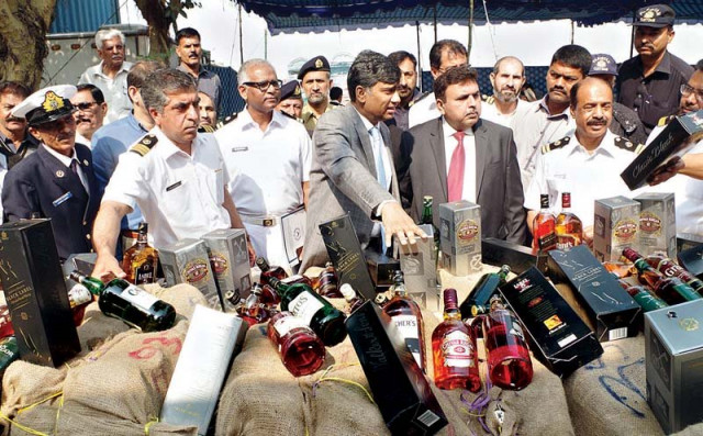 officials presenting liquor bottles that were seized by model collectorate of customs when they were being smuggled into the city photo online