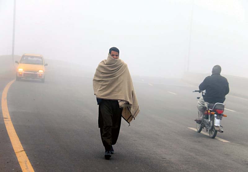 a man walks through thick fog on charsadda road peshawar photo muhammad iqbal express