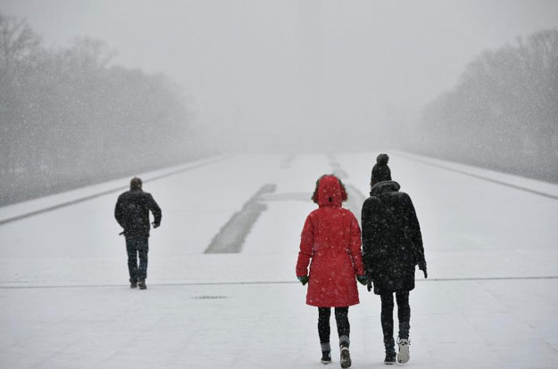 visitors walk under snowfall in front of the lincoln memorial on january 22 2016 in washington dc photo afp