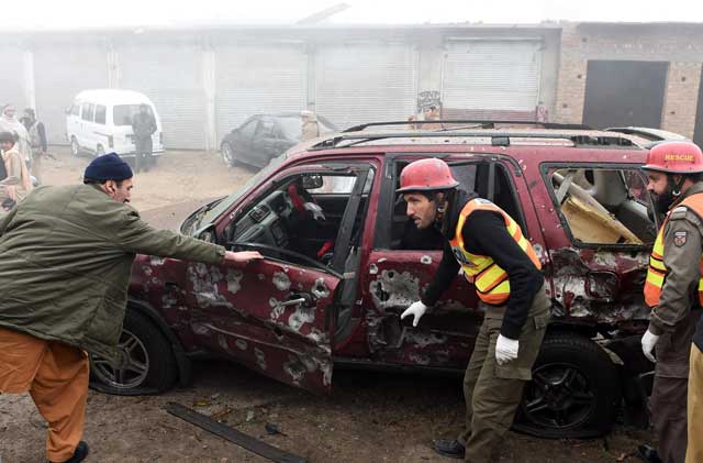 rescue workers search a damaged vehicle after a roadside bomb explosion in peshawar on january 24 2016 photo afp