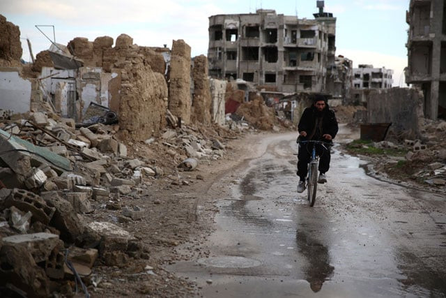 a syrian man rides a bike in the neighbourhood of jobar on the eastern outskirts of the capital damascus on january 23 2016 photo afp a syrian man rides a bike in the neighbourhood of jobar on the eastern outskirts of the capital damascus on january 23 2016 photo afp