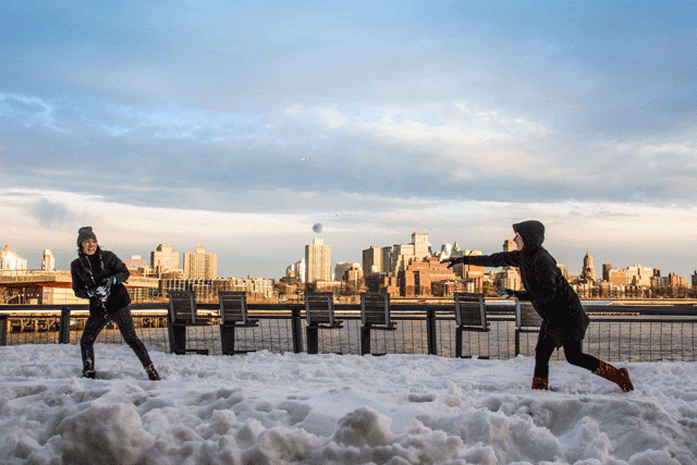 two girls are throwing snow balls at each other on the banks of financial district with brooklyn in the background on january 24 2016 in new york a massive blizzard that claimed at least 16 lives in the eastern united states finally appeared to be winding down sunday giving snowbound residents the chance to begin digging out photo afp