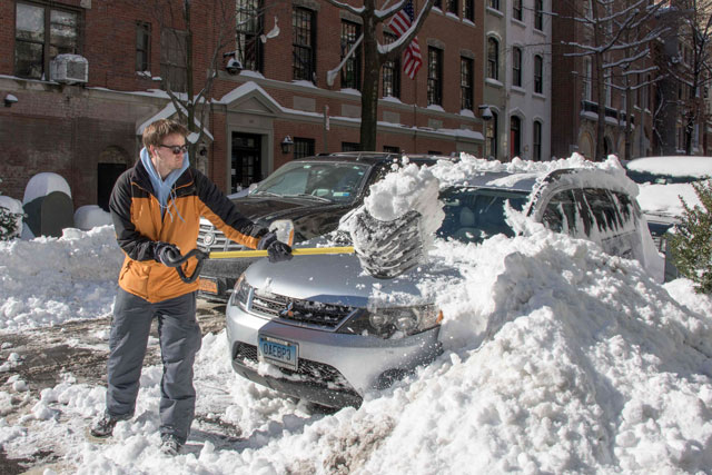 a man clears his car with a shovel near central park on january 24 2016 in new york photo afp