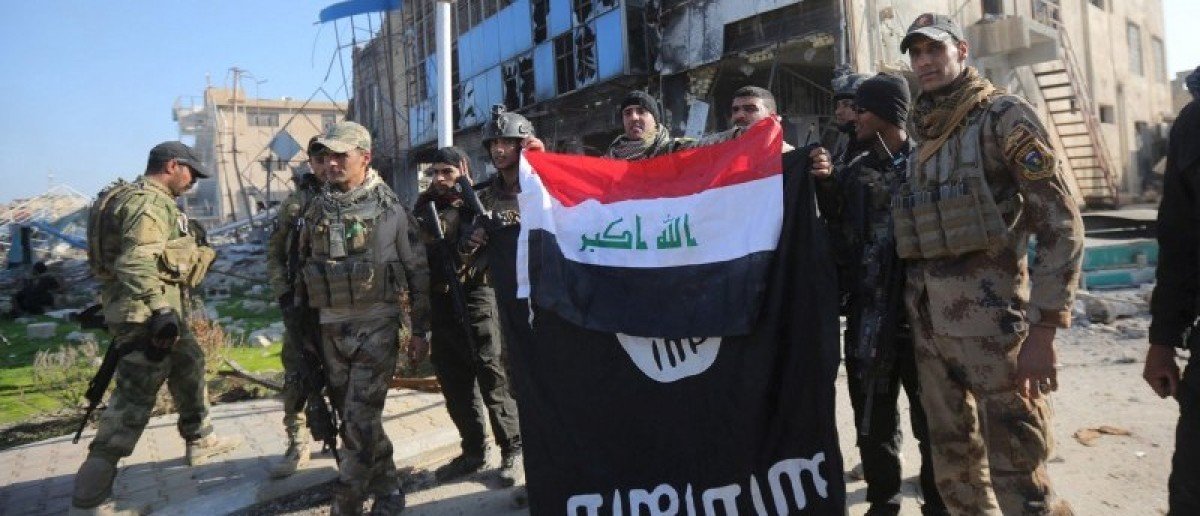 members of the iraqi security forces hold an iraqi flag with an islamic state flag which they had pulled down at a government complex in the city of ramadi december 28 2015 photo reuters