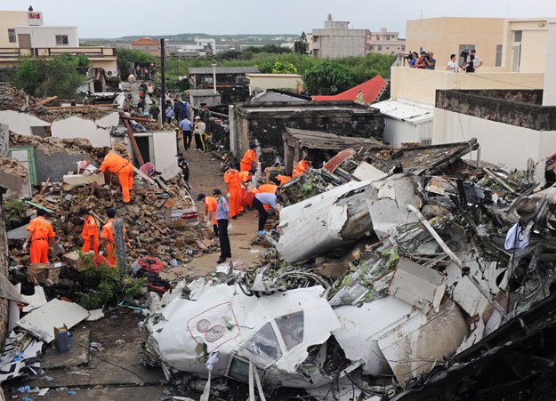 this picture taken on july 24 2014 shows rescue workers and firefighters searching through the wreckage where transasia airways flight ge222 crashed the night before near the airport at magong on the penghu island chain on july 24 2014 photo afp