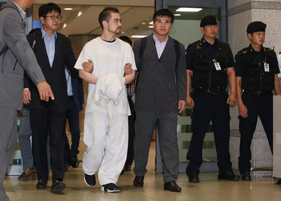 us national arthur patterson in white is escorted as he arrives at incheon international airport after being extradited from the us on september 23 2015 photo afp us national arthur patterson in white is escorted as he arrives at incheon international airport after being extradited from the us on september 23 2015 photo afp