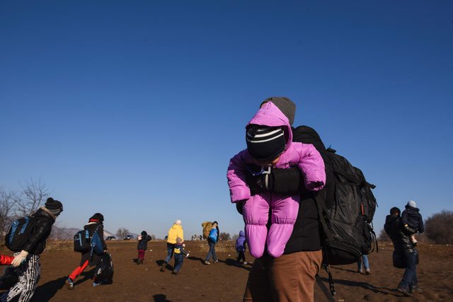 a man holds his baby as migrants and refugees walk near the village of miratovac after crossing into serbia via the macedonian border on january 30 2016 photo afp